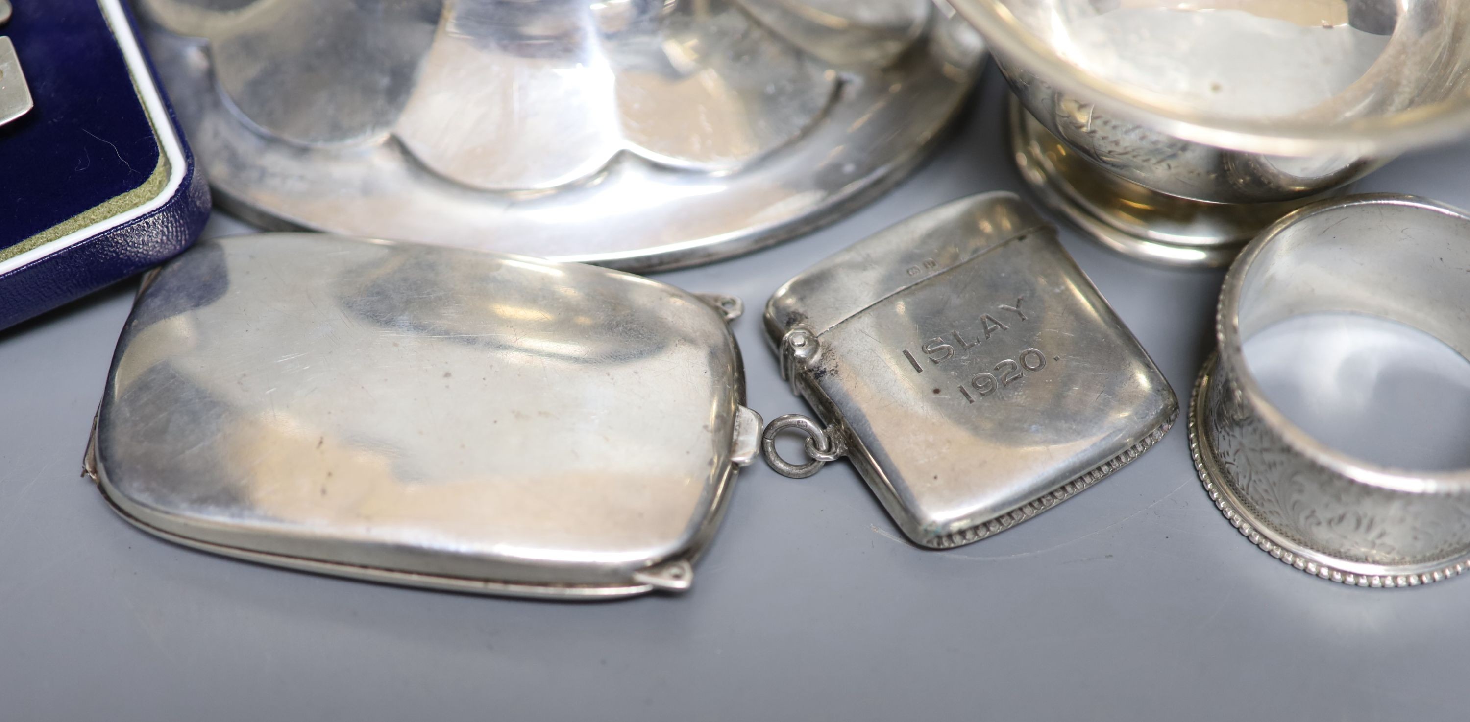 A Scottish silver mounted oval inkwell, 13.2cm, a small silver bowl, silver vesta case, silver cigarette case, two silver napkin rings and two other items.